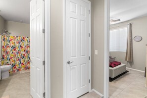 A bathroom with a shower, toilet, and a small seating area with a bench and a clock on the wall. - Goodyear Retreat, Pool, Slide, Firepit, BBQ (Goodyear)