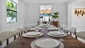 Una sala menjador amb una taula de fusta allargada preparada per a sis, envoltada per sis cadirees.