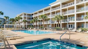 Un hotel amb una àrea de piscina gran, diversos balcons i palmeres.