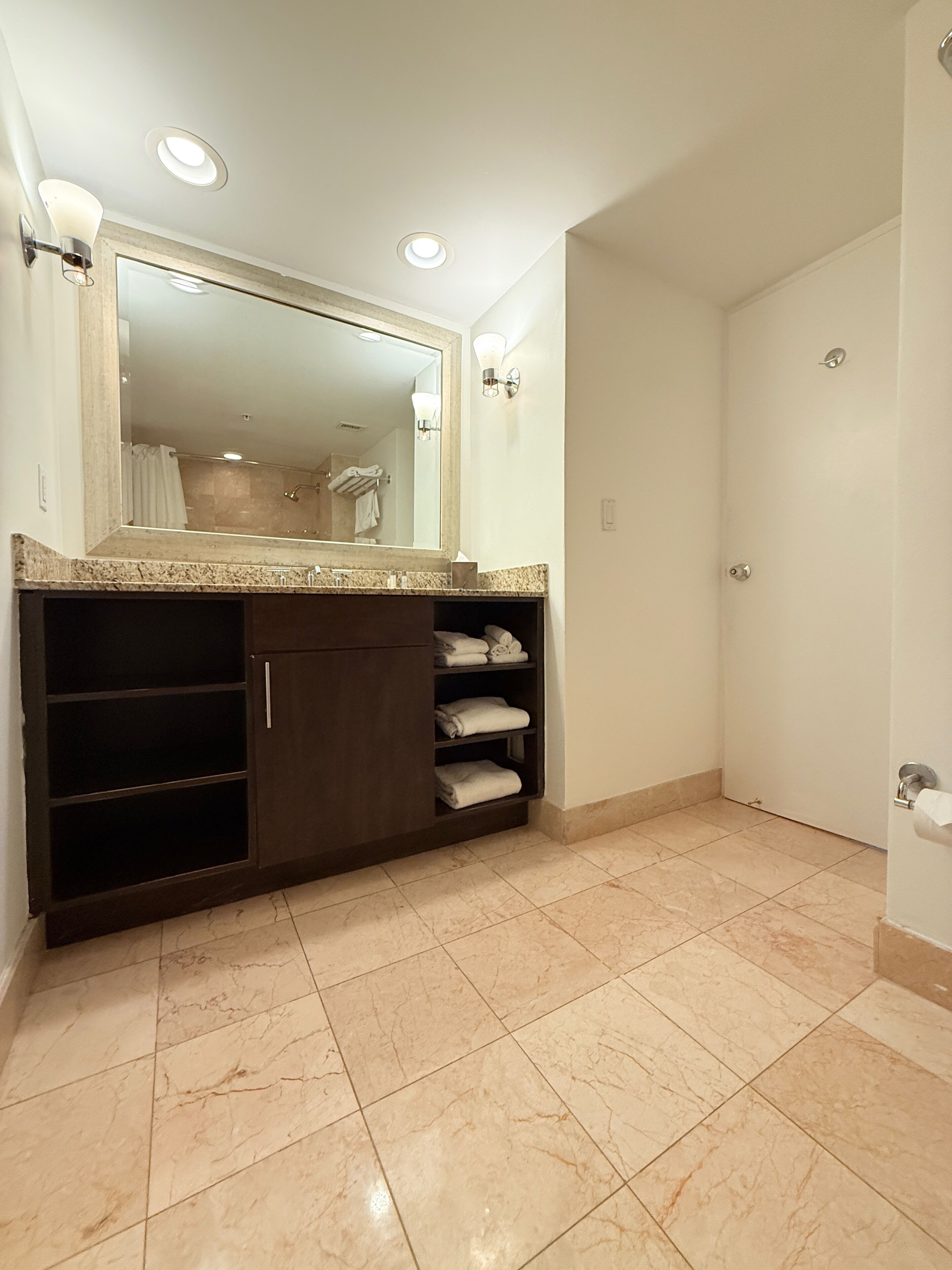 A bathroom with a large mirror, built-in shelves, and a shower area.