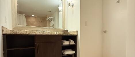 A bathroom with a large mirror, built-in shelves, and a shower area.