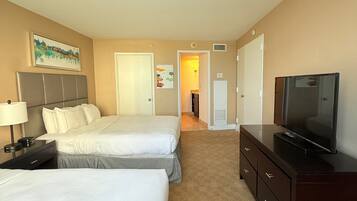 A hotel room with two beds, a TV, a dresser, and a painting on the wall.