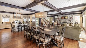 A spacious dining area with a large wooden table and chairs, a chandelier, and a stone fireplace. - 6 bed 6 bath cottage on Lake Joseph (Port Carling)