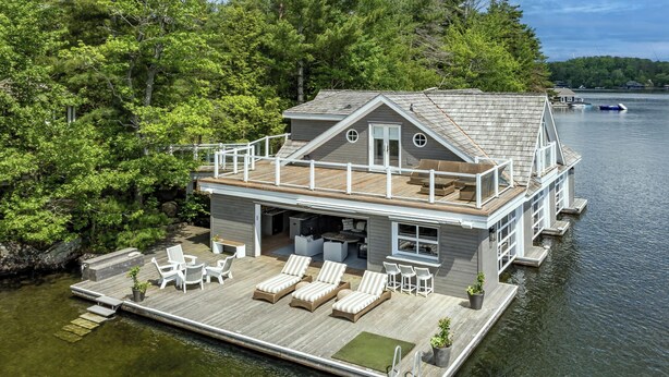 A houseboat with a deck, lounge chairs, and a covered outdoor area. - 6 bed 6 bath cottage on Lake Joseph (Port Carling)