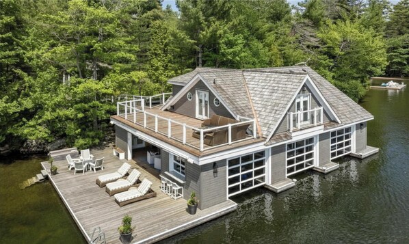 Una casa flotante con terraza, asientos al aire libre y un muelle.