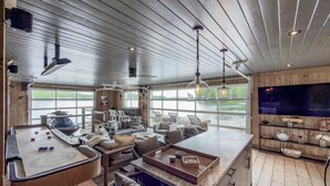 A modern interior with a kitchen, dining area, and large windows overlooking a body of water. - 6 bed 6 bath cottage on Lake Joseph (Port Carling)