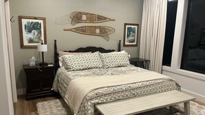 A bedroom with a bed, bedside tables, a bench, and two wall-mounted decorations. - Lanes End: Spacious Lakefront Retreat in Scenic Grand Marais (Grand Marais)
