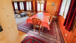En inredning med träpanel och ett matbord för sex personer, omgivet av stolar, och en mönstrad matta på golvet.