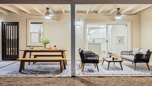 A cozy living area with a wooden table set for dining, a sofa, and a chair. A kitchen is visible in the background. - Fire Pit & Covered Patio Near Old Town Scottsdale Arcadia Haven by Avantstay (Phoenix)