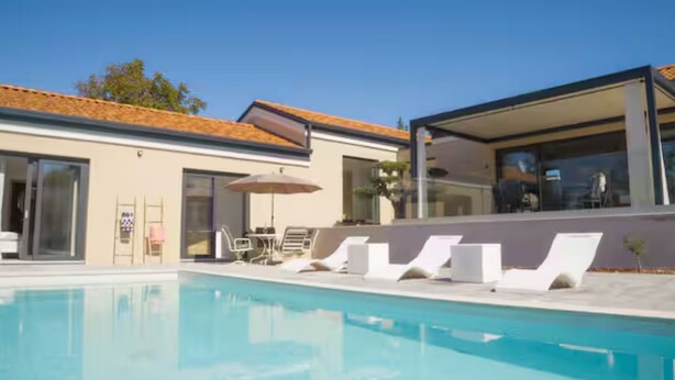 A modern pool area with lounge chairs and a glass-enclosed structure. - Villa in Paradise With Heated Pool (Sveta Nedelja)