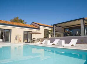A modern pool area with lounge chairs and a glass-enclosed structure. - Villa in Paradise With Heated Pool (Sveta Nedelja)