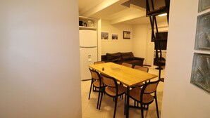 Un espacio habitable compacto con comedor que incluye una mesa de madera y sillas negras, un sofá y un refrigerador.