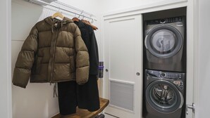 A laundry room with a washing machine and dryer, a bench, and clothes hanging on a rack. - Mackenzie Mountain Hop (Revelstoke)