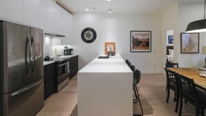 A modern kitchen with a central island, stainless steel appliances, and a dining area with a wooden table and chairs. - Mackenzie Mountain Hop (Revelstoke)