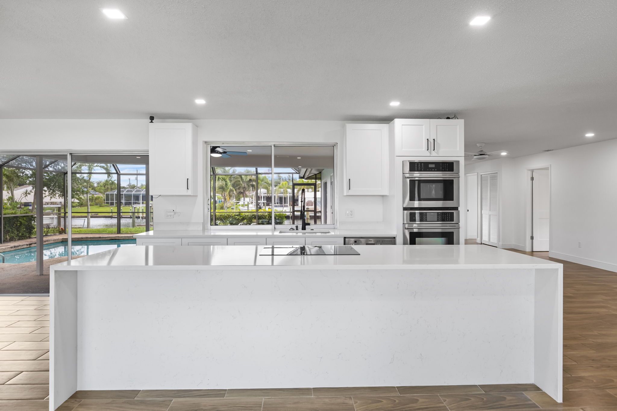 A modern kitchen with a large island, built-in appliances, and a view of a pool.
