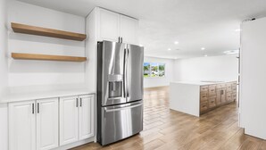 Una cucina moderna con mobili bianchi, elettrodomestici in acciaio inossidabile e pavimento in legno.