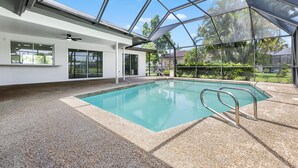 Una piscina interna con tetto in vetro, pavimentata con ciottoli e ampie finestre che offrono vista sul verde.