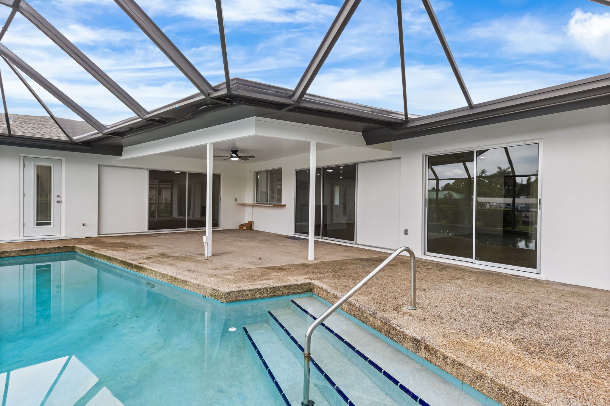 An indoor swimming pool with a skylight, a ceiling fan, and a view of the outside.