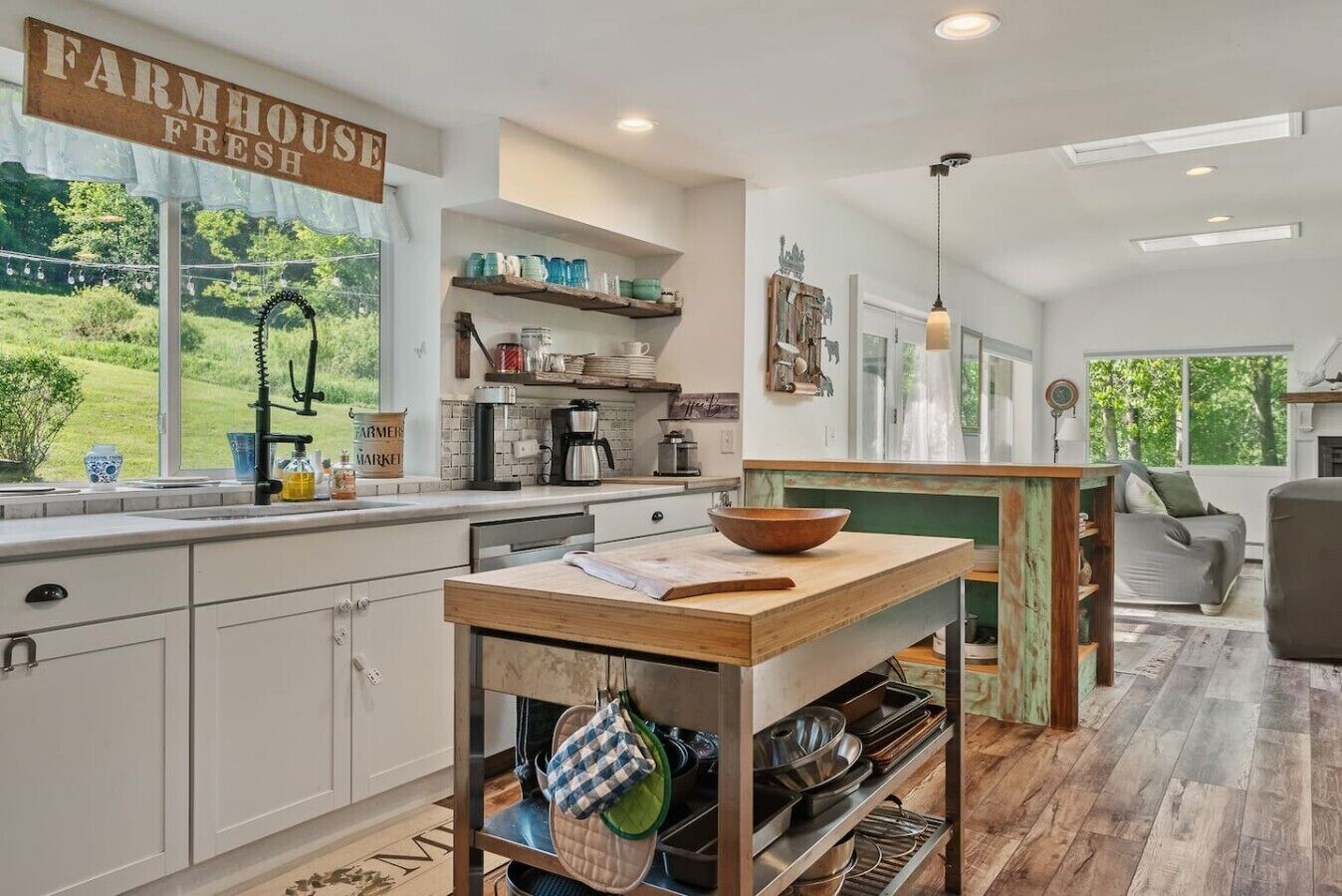 Une cuisine décorée dans le style d’une ferme, avec un panneau décoratif typique, une machine à café et une vue sur l’extérieur.