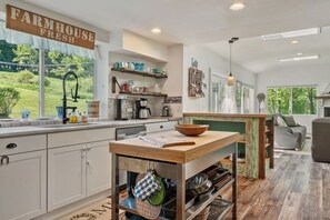 A kitchen with a farmhouse sign, a coffee maker, and a view of the outdoors. - Country Chic 3BR Retreat Near All Star Village (Treadwell)