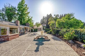 A courtyard with a central fountain, surrounded by a patio area and lush greenery.