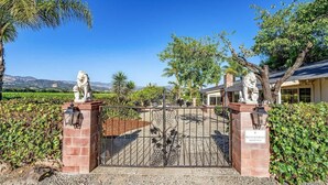 A gated entrance with statues, a private residence sign, and a view of a house and landscape. - Trentadue Winery Farmstay with Pool and Wine Tastings Included (Geyserville)