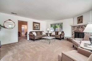 A living room with two sofas, a coffee table, a fireplace, and a door leading to another room.