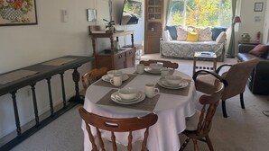 A dining area with a table set for four, a wooden chair, and a sofa in the background. - Spacious house in marvelous Healdsburg close to town (Healdsburg)
