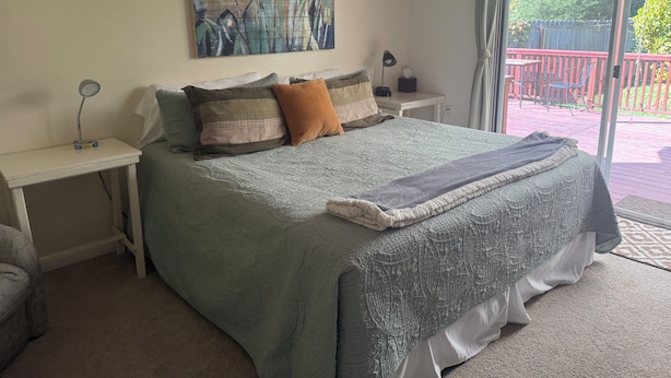 A bedroom with a large bed, a bedside table with a lamp, a painting on the wall, and a view of the outdoors through a sliding door. - Spacious house in marvelous Healdsburg close to town (Healdsburg)