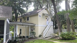 Une maison à deux étages avec un porche à l’avant, un petit jardin et un escalier menant à l’étage supérieur.