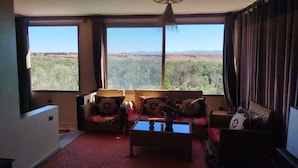 A living room with a large window, two sofas, a coffee table, and a hanging light fixture. - Amlal Kasbah (Souk Lakhmis Dades)