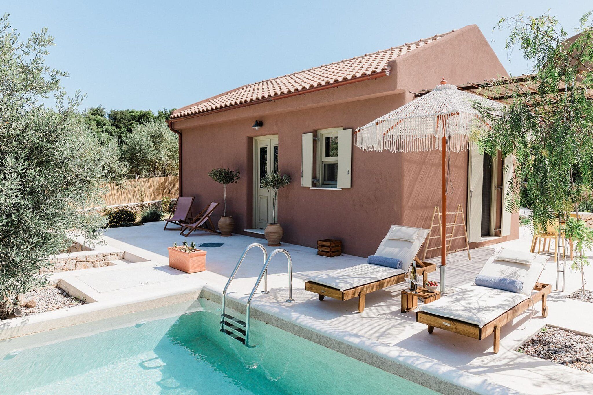 A poolside area with lounge chairs, a small pool, and a building with a tiled roof.