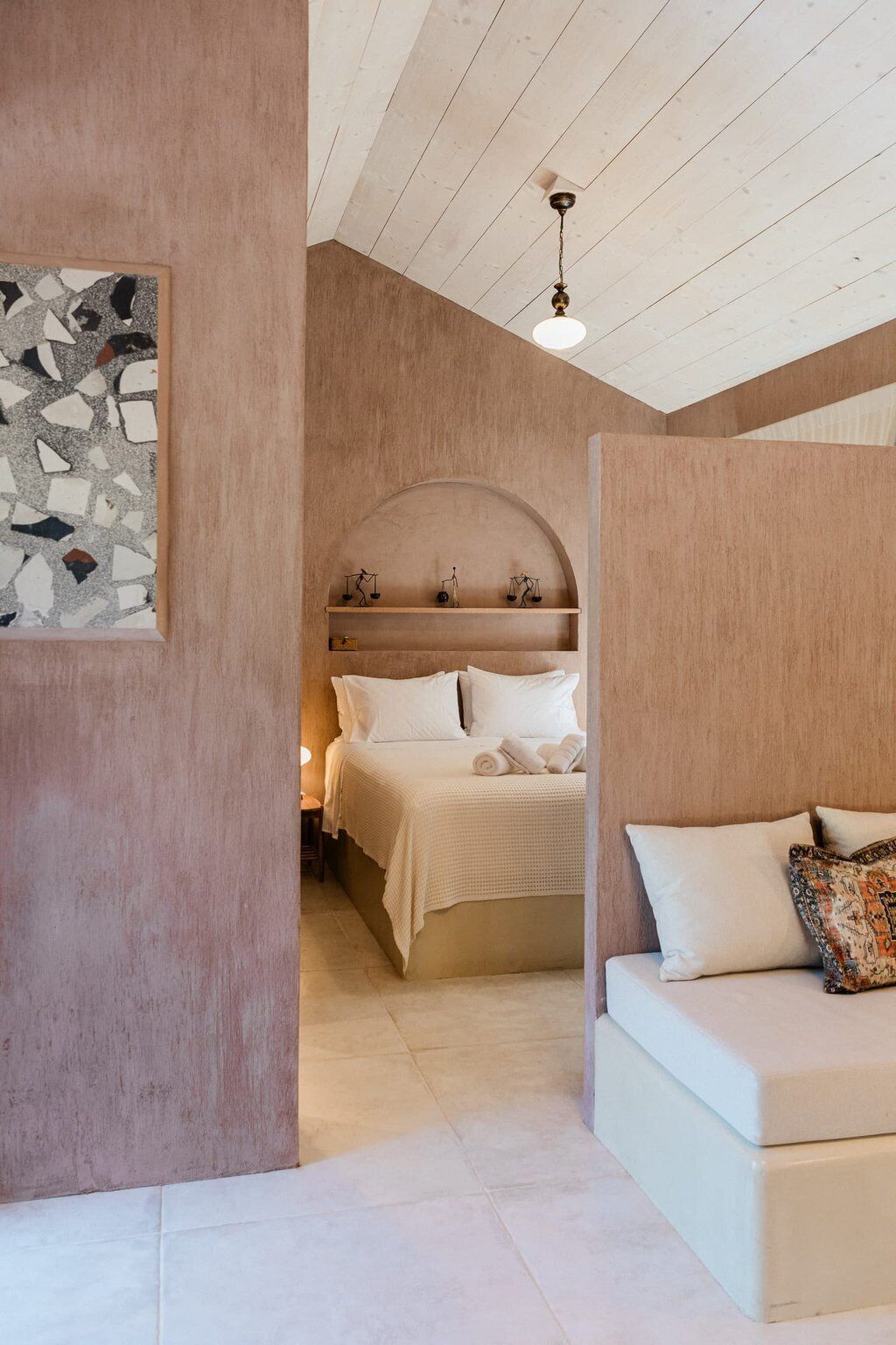 A bedroom with a bed, a sofa, and a wall-mounted shelf with scales.