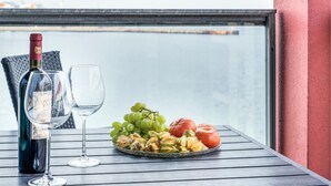 Ein Tisch mit einer Weinflasche, einem Glas und einer Schale Früchte und Nüssen.