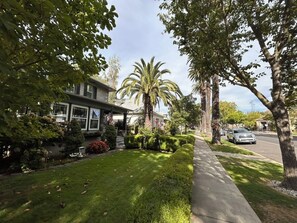 A residential street with a well-maintained lawn, a sidewalk, and a parked car.