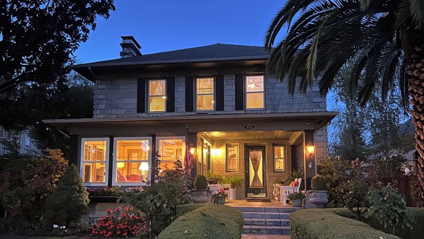 Una casa a due piani con un giardino curato, un portico e una bandiera americana.