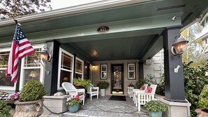 Una casa con veranda, bandiera americana e un cartello con il numero 411.