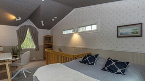 A bedroom with a large bed, a desk, and a window.