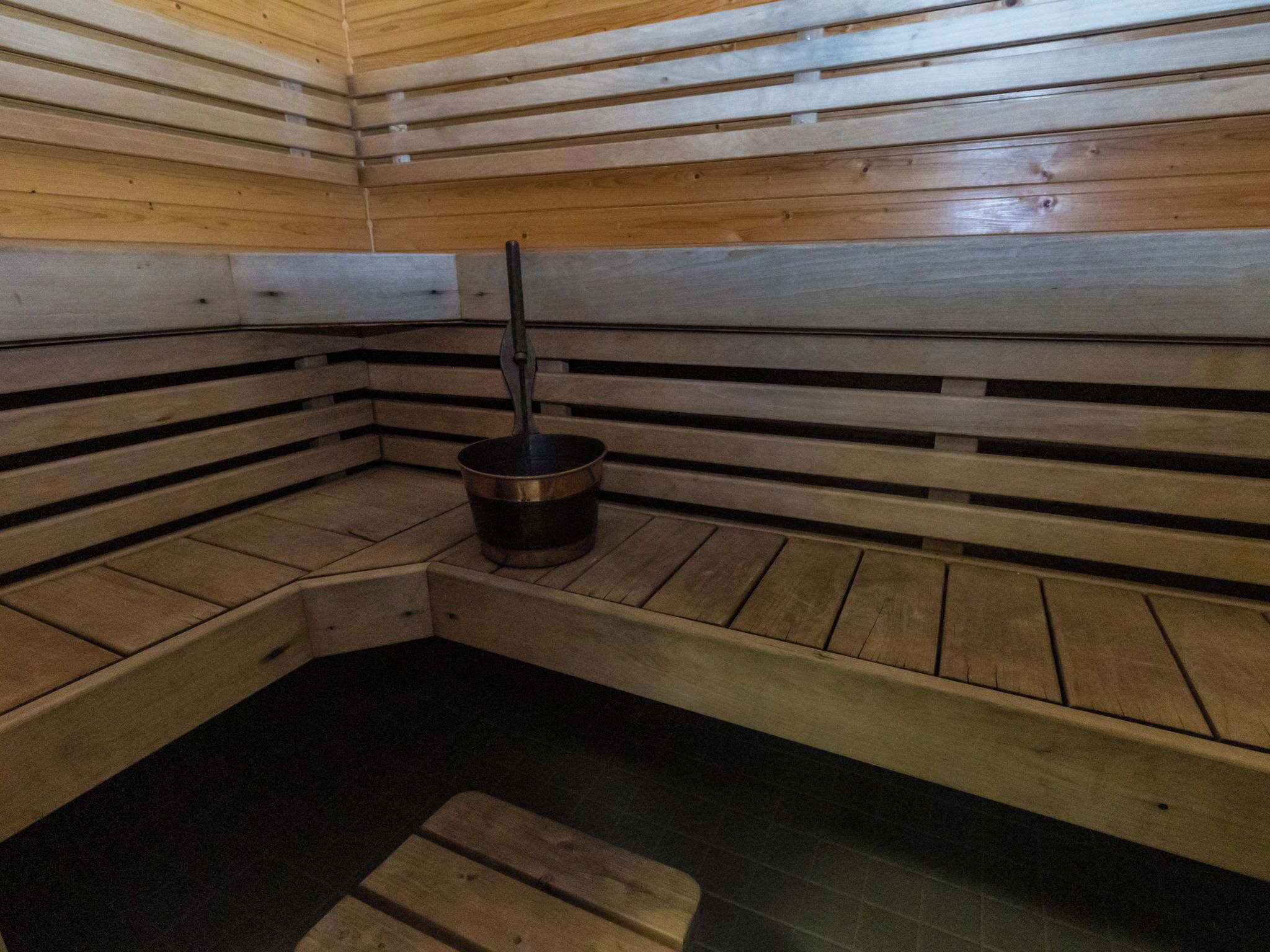 A sauna with wooden benches and a central heating element.
