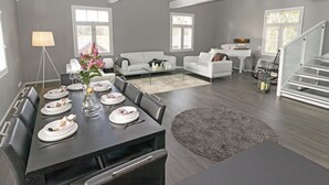 A spacious living room with a dining area, grey walls, and a staircase. - Villa torppa by Interhome (Eura)