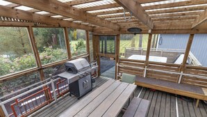 An outdoor deck with a wooden pergola, a barbecue grill, and a seating area with benches and a table. - Villa torppa by Interhome (Eura)