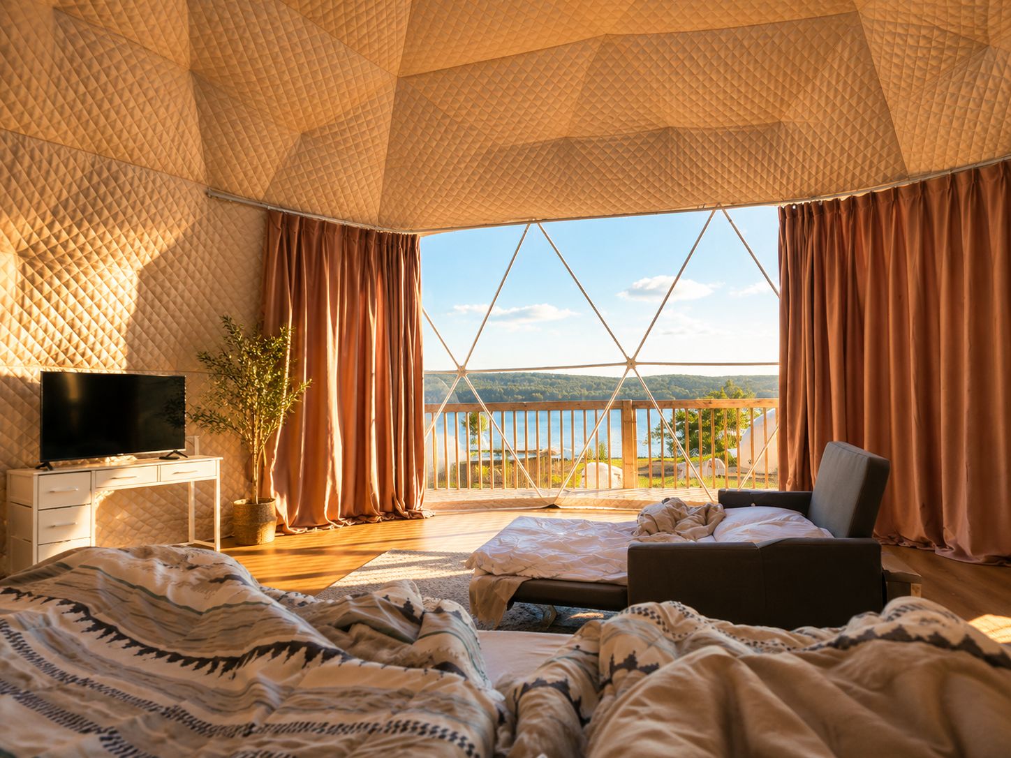 A bedroom with a large window, a bed, a TV, and a wooden desk.