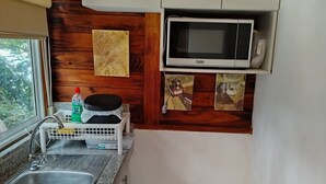A compact kitchen with white cabinets, a built-in microwave, and a granite countertop. - Nature, calm and comfort in a chalet close to everything but far from noise. (Guayaquil)