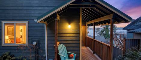 A wooden house with a covered porch, a chair, and a view of the water.