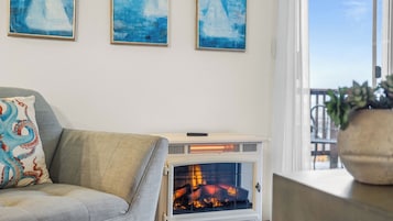 A living room with a sofa, a fireplace, and three blue paintings on the wall.