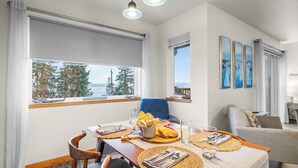 A dining area with a table set for two, a blue chair, and a view of the sea. - Cozy Whidbey Island Home Near Langley Waterfront & Dining Tideview by Avantstay (Langley)