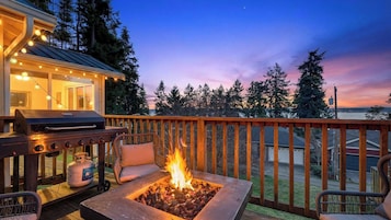 A deck with a grill, a fire pit, and outdoor seating.