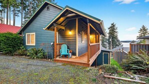 A small, single-story house with a porch, a blue chair, and a wooden deck. - Cozy Whidbey Island Home Near Langley Waterfront & Dining Tideview by Avantstay (Langley)