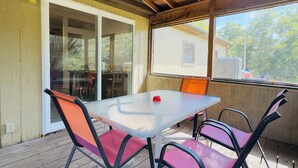 An outdoor patio with a table and chairs, a sliding glass door, and a view of a house in the background. - Restful, 2b/1b Unit along the Gasconade River (Richland)