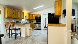 A spacious kitchen with wooden cabinets, a stainless steel refrigerator, and a built-in oven. - Restful, 2b/1b Unit along the Gasconade River (Richland)